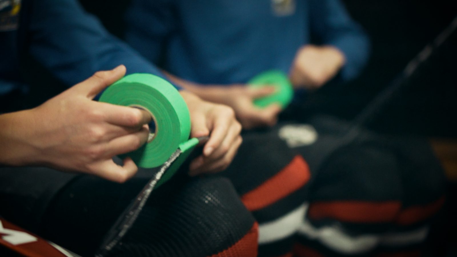 Hands holding two rolls of green Buddy Check tape